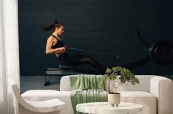 Fototapeta: Side view of young muscular woman exercising in gym with rowing