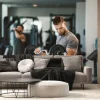 Fototapeta: Young bearded man doing biceps exercises in gym with barbell