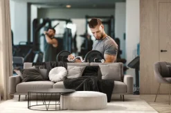 Fototapeta: Young bearded man doing biceps exercises in gym with barbell