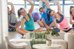 Fototapeta: Zajęcia fitness i instruktor siedzi i rozciągając ręce