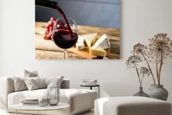 Obraz: Wylewanie czerwonego wina do szklanki na drewnianym stole