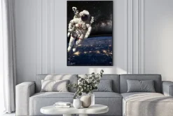 Plakat: Astronauta w przestrzeni kosmicznej nad ziemią w porze nocnej.