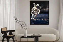 Plakat: Astronauta w przestrzeni kosmicznej nad ziemią w porze nocnej.