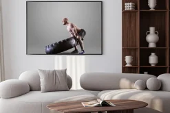 Plakat: Athletic młody człowiek podnoszenia oponę na szarym tle studio