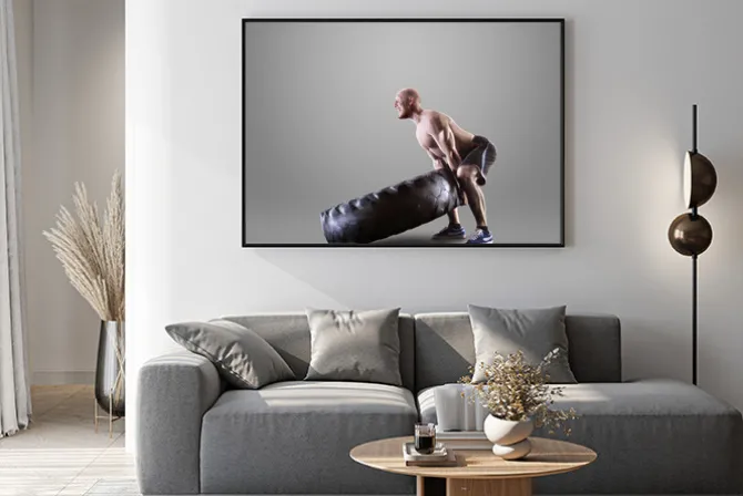 Plakat: Athletic młody człowiek podnoszenia oponę na szarym tle studio