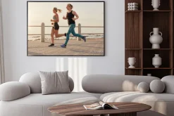 Plakat: Młode kobiety biegnące wzdłuż nadmorskiej promenady