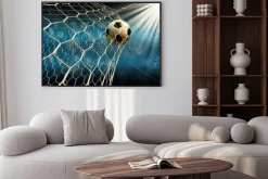 Plakat: Piłka nożna wpadająca do bramki na tle reflektorów