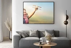 Plakat: Wolność marzyć - radosne dziecko gra z samolotu na tle nieba